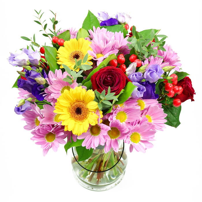 A lush, garden-style bouquet is captured here in a straightforward glass vase, positioned against a bright white background that makes every colour appear crisp and true. The arrangement is full and rounded, led by several deep crimson roses whose velvety petals curl inward like tiny whirlpools of colour. Close to them, two bright yellow gerbera daisies with dark, chocolate-amber centres stand out with their wide, flat faces, giving the bouquet a lively, almost sunlit personality. Around this strong core, you can see generous sprays of blush-pink daisies or chrysanthemums, each tiny flower composed of many slender petals radiating from a soft yellow centre, building volume and a sense of gentle movement. Threaded between these pastel blooms are stems of purple and lavender lisianthus, their bell-shaped blossoms and softly ruffled edges adding sophistication and a cool contrast to the warmer tones. Dotted through the bouquet, small clusters of smooth red hypericum berries catch the light like polished beads, adding both colour intensity and tactile interest. An array of green foliage, from broad, glossy leaves to finer, lighter sprigs, frames and supports the flowers, giving the composition a natural, freshly gathered look. Through the clear glass of the vase, the stems can be seen criss-crossing in clear water, carefully trimmed and arranged with intention. This bouquet feels perfect for joyful occasions-a birthday in a Harefield cottage near the common, a thank-you surprise for someone on a quiet lane, or a centrepiece for a family celebration overlooking the canal. It evokes that feeling of opening the door to a same-day flower delivery, arms full of colour and the soft, mixed fragrance of fresh blooms.